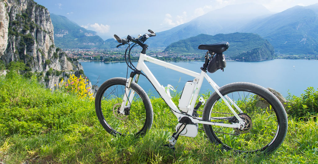 Guidon de vélo électrique avec écran d'assistance et paysage du lac d'Annecy en arrière-plan flou